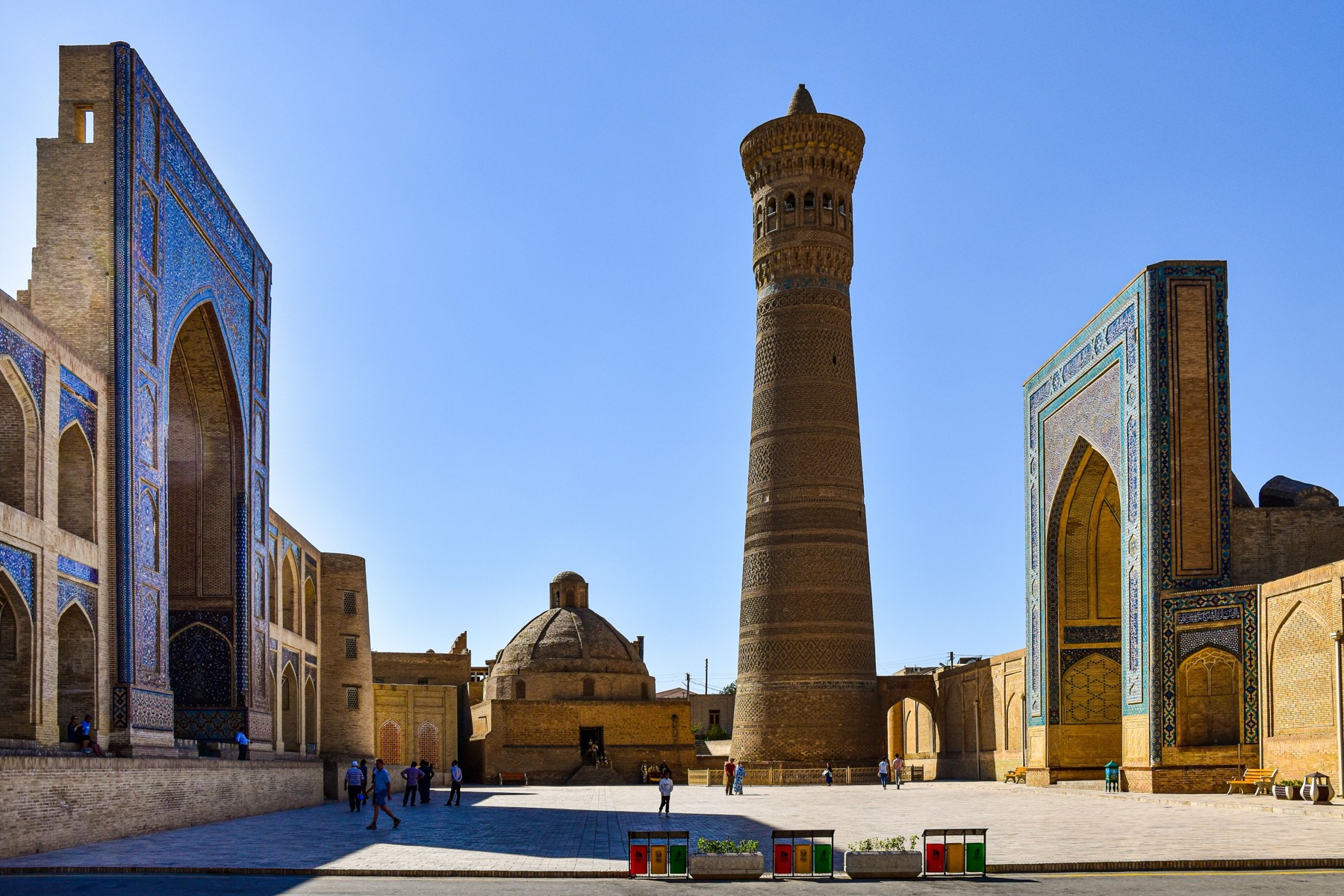 The Kalyan Minaret in daylight, with the Mir-i-Arab Madrasa's blue tilework to one side of the square.