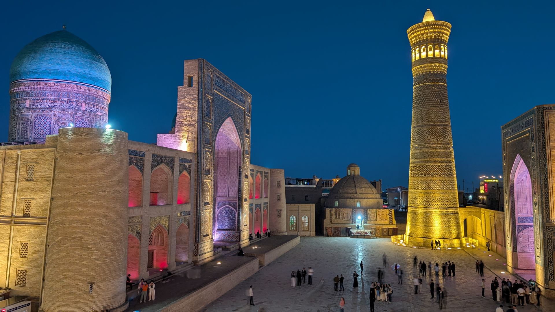 Poi Kalyan complex in Bukhara lit up at night, with the Kalyan Minaret rising over the square.